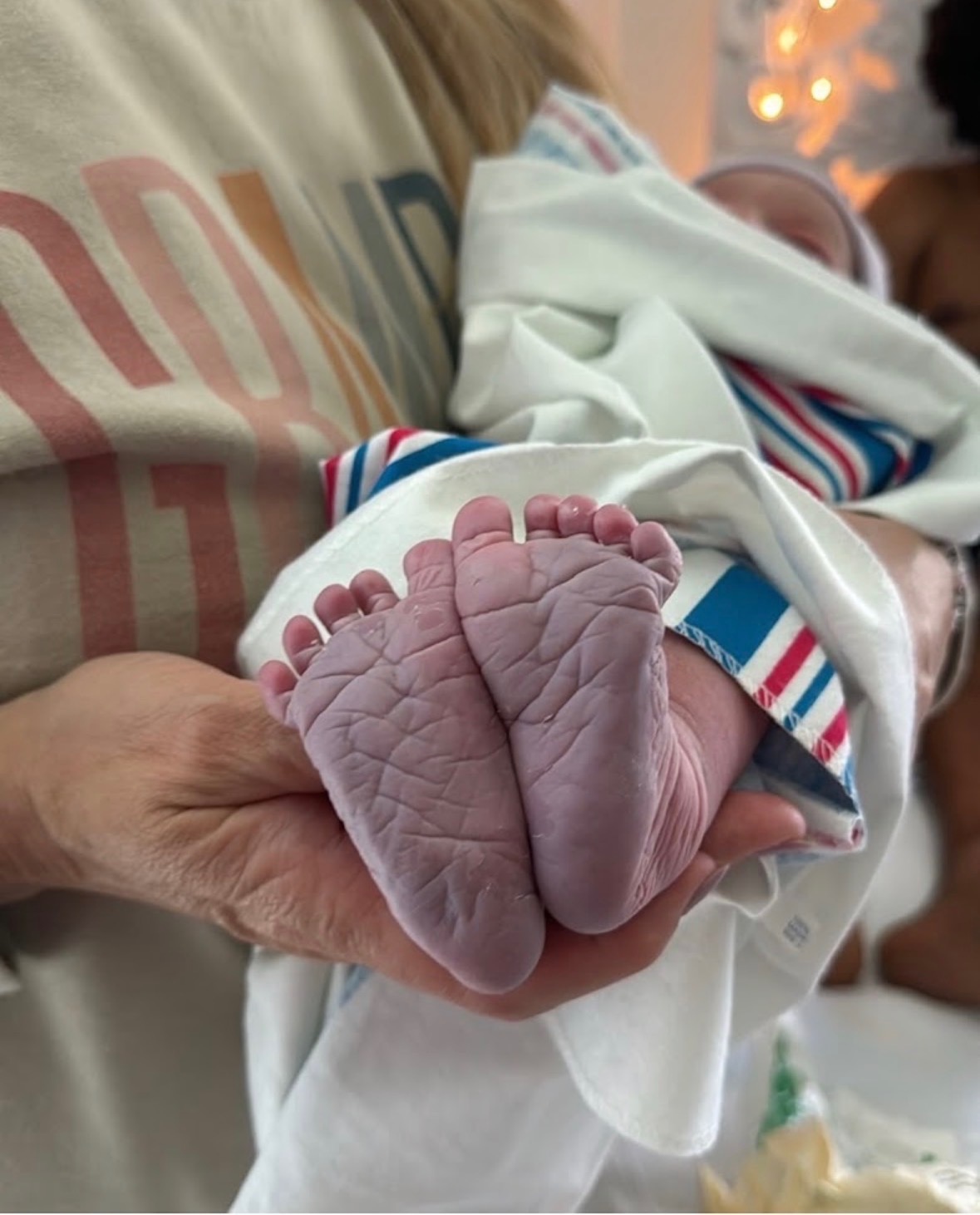 A newborn's wrinkled feet cradled in an adult's hand