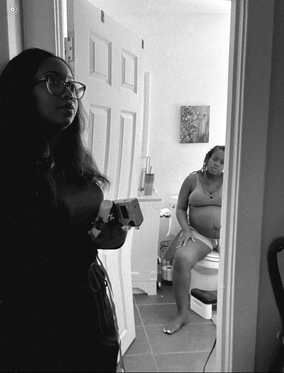 Black and white photo of a birth worker checking baby's heart tones while a laboring mother rests in the bathroom